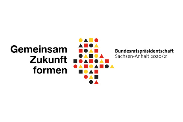 Grafik zeigt das Logo für Bundesratspräsidentschaft Sachsen-Anhalts und Tag der Deutschen Einheit 2021 – Das Logo kombiniert die drei Grundformen des Bauhauses mit den Farben Schwarz, Rot und Gold zu ein stilisierten Silhouette des Landes
